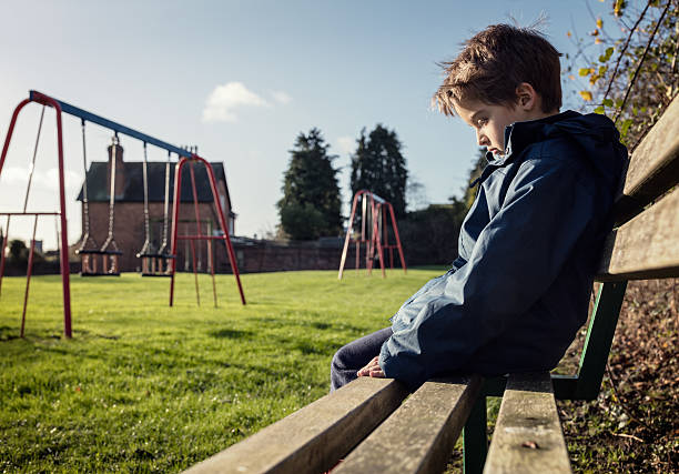 A child standing alone beside an empty playground